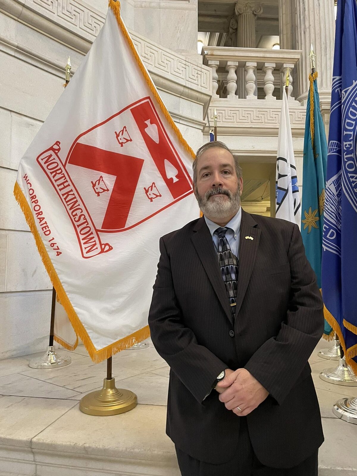 Matt McCoy standing beside the North Kingstown flag at the Rhode Island State House